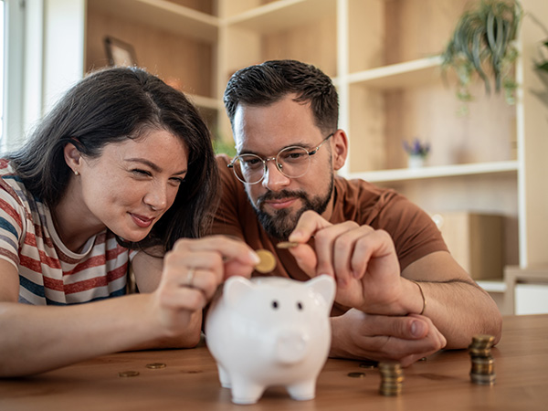 Junges Paar spart Geld in einem Sparschwein