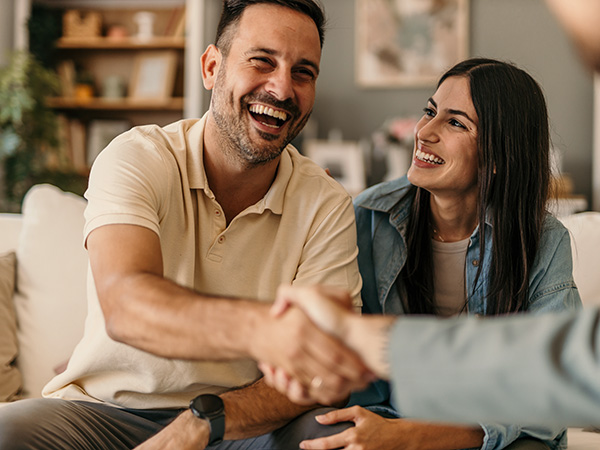 Junges Paar schüttelt Hand von Versicherungsmakler
