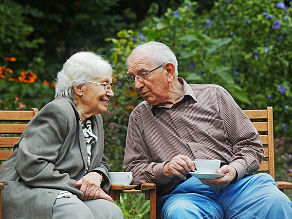Altes Ehepaar sitzt im Garten und trinkt Tee