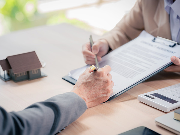 Verträge werden besprochen, Miniaturhaus steht auf dem Schreibtisch